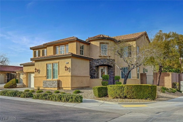 mediterranean / spanish-style home featuring a tiled roof, stone siding, a garage, fence, and stucco siding