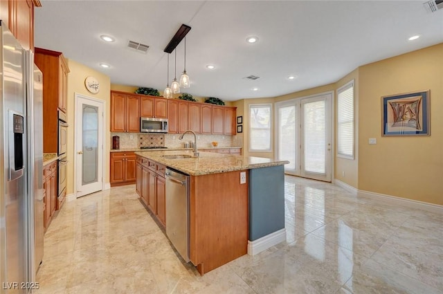 kitchen with a kitchen island with sink, marble finish floor, a sink, stainless steel appliances, and backsplash