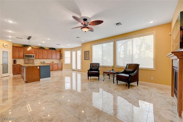 living room featuring ceiling fan, a glass covered fireplace, visible vents, marble finish floor, and baseboards