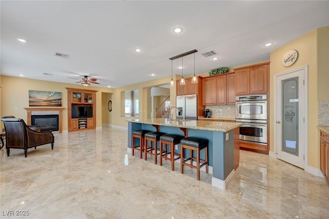 kitchen featuring visible vents, appliances with stainless steel finishes, marble finish floor, and a kitchen breakfast bar