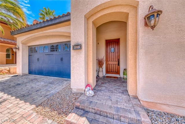 1045 Via Camelia St, Henderson, NV 89011 - entrance to property featuring a garage, stucco siding, and decorative driveway