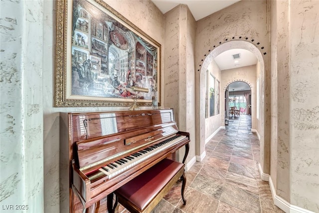 1045 Via Camelia St, Henderson, NV 89011 - hallway with arched walkways, visible vents, baseboards, and stone tile flooring