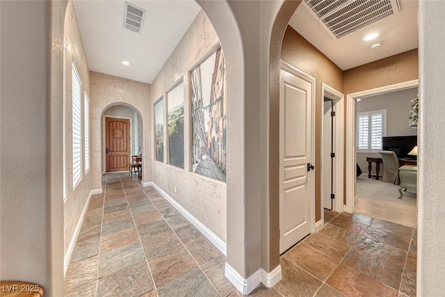1045 Via Camelia St, Henderson, NV 89011 - hallway featuring arched walkways, visible vents, baseboards, and stone tile flooring
