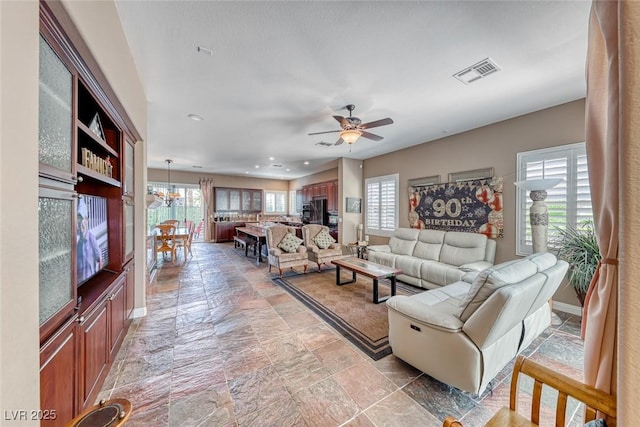 1045 Via Camelia St, Henderson, NV 89011 - living room with visible vents, ceiling fan, stone tile floors, and baseboards