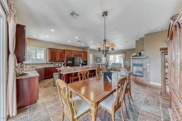 1045 Via Camelia St, Henderson, NV 89011 - dining space featuring a notable chandelier, a glass covered fireplace, visible vents, and a wealth of natural light