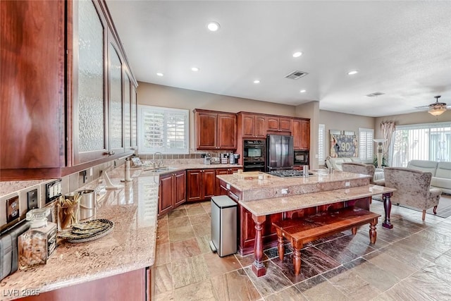 1045 Via Camelia St, Henderson, NV 89011 - kitchen with visible vents, a sink, open floor plan, a kitchen bar, and black appliances