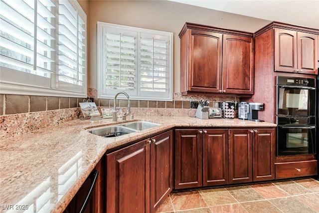 1045 Via Camelia St, Henderson, NV 89011 - kitchen with light stone counters, dobule oven black, stone finish floor, decorative backsplash, and a sink