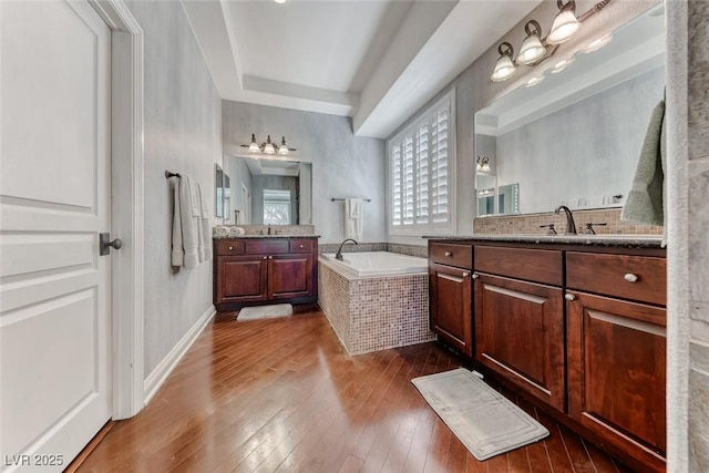 1045 Via Camelia St, Henderson, NV 89011 - bathroom featuring two vanities, a garden tub, hardwood / wood-style flooring, and a sink
