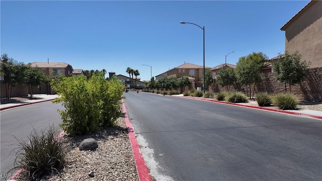view of street featuring curbs, a residential view, street lights, and sidewalks