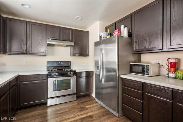 kitchen with dark wood finished floors, dark brown cabinetry, under cabinet range hood, light countertops, and stainless steel appliances