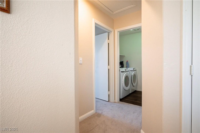 hallway featuring separate washer and dryer and light colored carpet