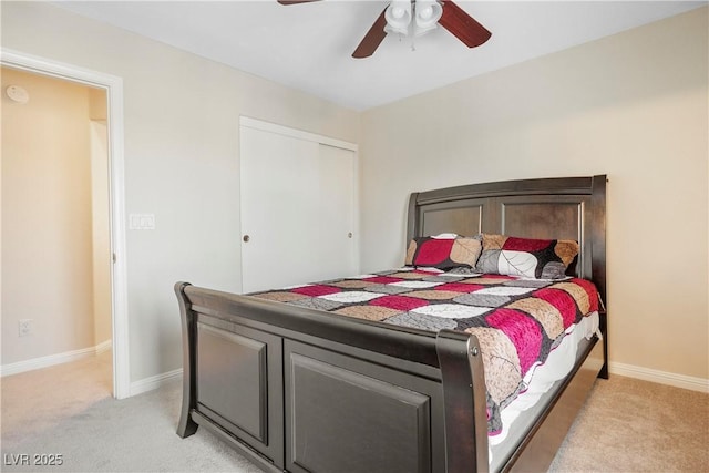 bedroom featuring light carpet, a closet, baseboards, and a ceiling fan