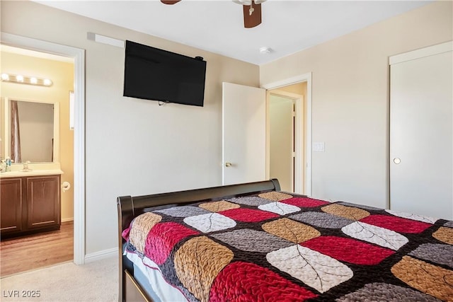 bedroom featuring a ceiling fan, ensuite bath, and light carpet