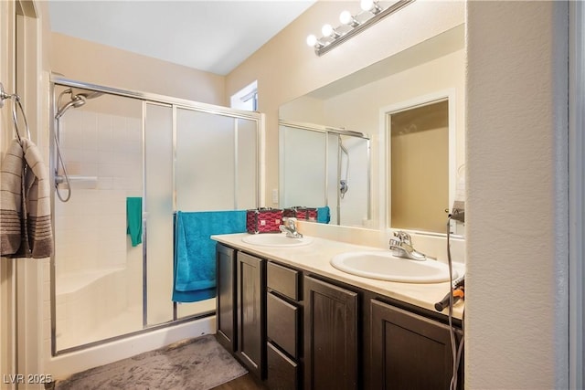 full bathroom featuring a stall shower, double vanity, and a sink