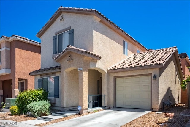 mediterranean / spanish home with a tiled roof, a garage, driveway, and stucco siding