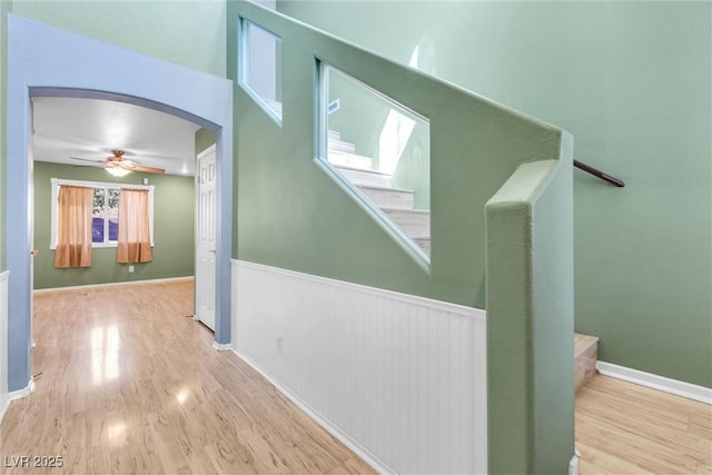 hallway featuring arched walkways, stairway, and wood finished floors