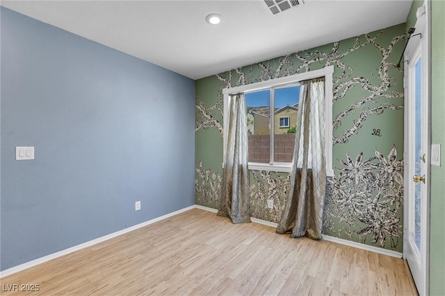 empty room with wood finished floors, baseboards, and visible vents