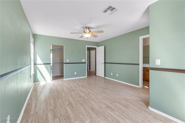 spare room featuring visible vents, light wood-type flooring, a ceiling fan, and baseboards