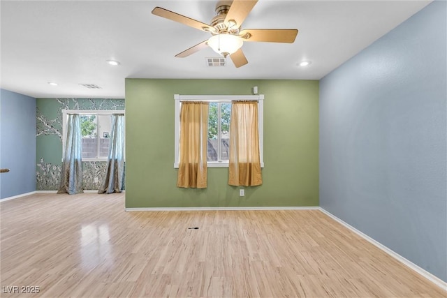 spare room with a healthy amount of sunlight, visible vents, and wood finished floors