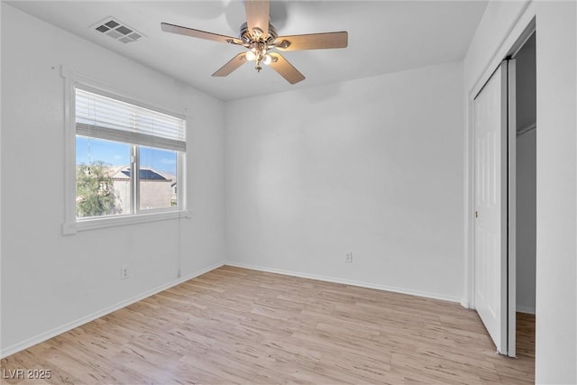 unfurnished bedroom with a closet, a ceiling fan, visible vents, light wood finished floors, and baseboards