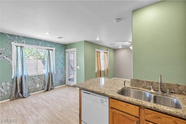 kitchen with baseboards, light wood-style flooring, visible vents, dishwasher, and a sink