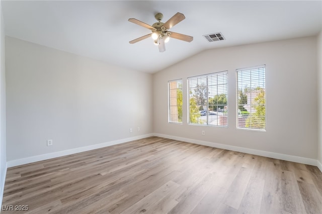 spare room with lofted ceiling, light wood-style floors, a ceiling fan, and baseboards