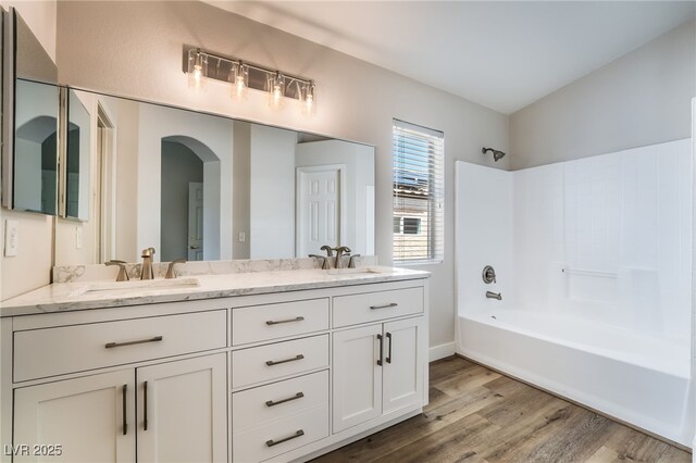 bathroom with wood finished floors,  shower combination, and double vanity
