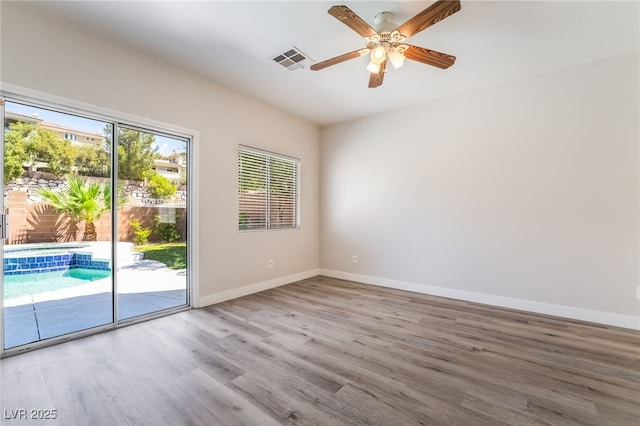 unfurnished room with wood finished floors, baseboards, and ceiling fan