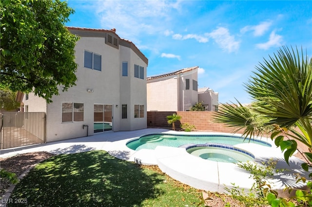 view of swimming pool featuring a fenced backyard, a pool with connected hot tub, and a patio