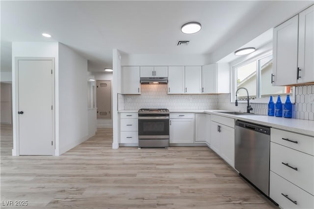 1808 E Saint Louis Ave, Las Vegas, NV 89104 - kitchen featuring appliances with stainless steel finishes, under cabinet range hood, a sink, light countertops, and white cabinets