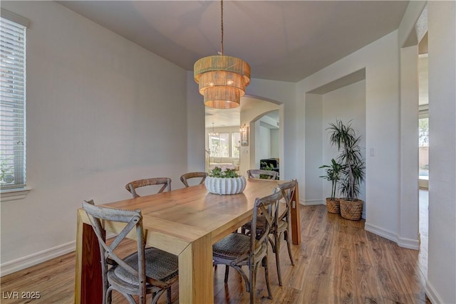 9992 Sky Parlor Rd, Las Vegas, NV 89178 - dining room featuring baseboards, arched walkways, a notable chandelier, and light wood-style floors