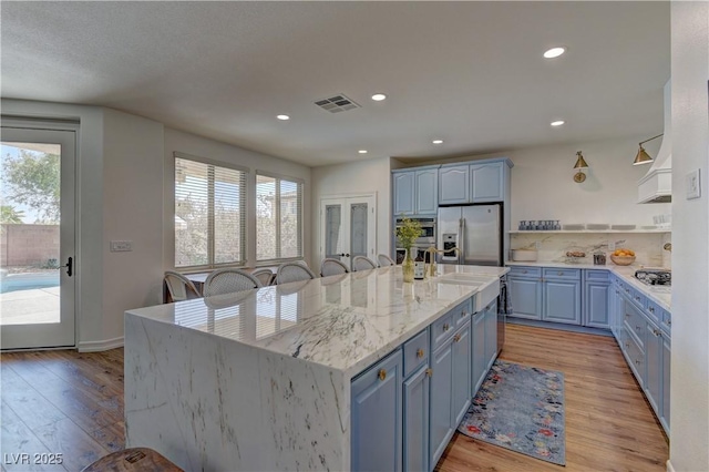 9992 Sky Parlor Rd, Las Vegas, NV 89178 - kitchen featuring a wealth of natural light, appliances with stainless steel finishes, blue cabinets, and light wood finished floors