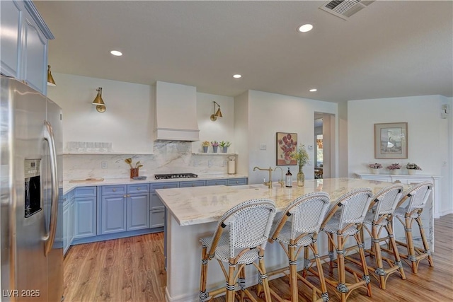 9992 Sky Parlor Rd, Las Vegas, NV 89178 - kitchen featuring light wood-style flooring, appliances with stainless steel finishes, custom range hood, and a kitchen breakfast bar