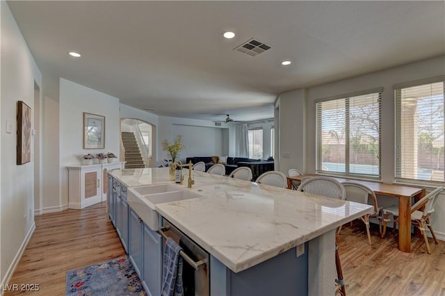 9992 Sky Parlor Rd, Las Vegas, NV 89178 - kitchen with a breakfast bar, a sink, visible vents, light wood finished floors, and blue cabinets