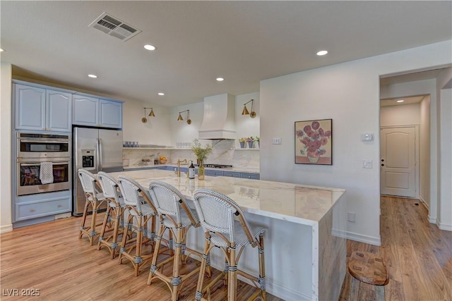 9992 Sky Parlor Rd, Las Vegas, NV 89178 - kitchen with custom range hood, light stone counters, recessed lighting, visible vents, and appliances with stainless steel finishes