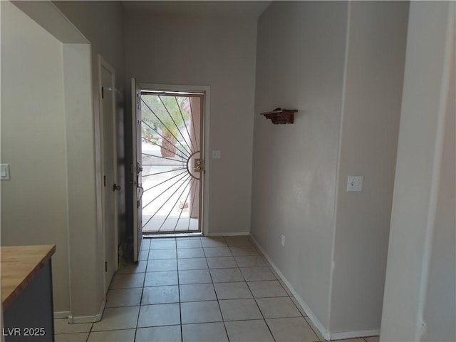 doorway featuring light tile patterned floors and baseboards