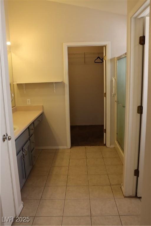 bathroom featuring tile patterned flooring, vanity, a walk in closet, and a stall shower