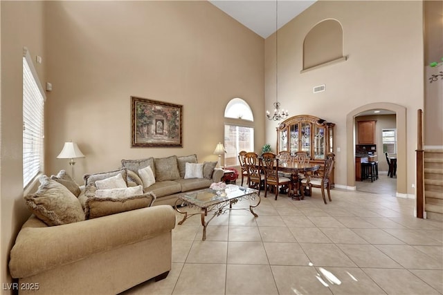living area featuring high vaulted ceiling, light tile patterned floors, arched walkways, visible vents, and baseboards
