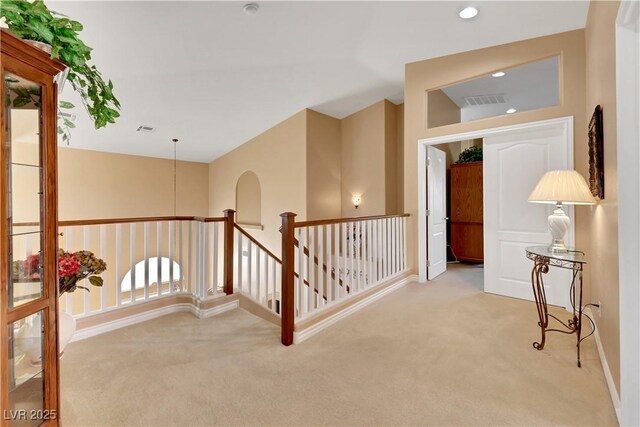 corridor with carpet, visible vents, and an upstairs landing