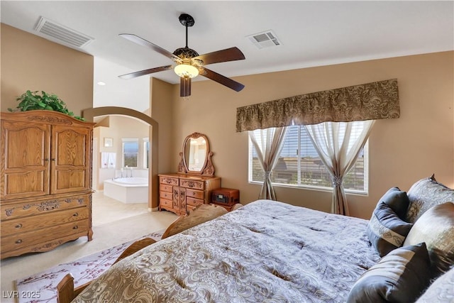 bedroom with visible vents, ceiling fan, arched walkways, and light colored carpet