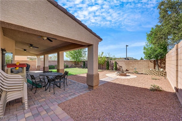 view of patio / terrace featuring outdoor dining space, a fenced backyard, an outdoor fire pit, and ceiling fan