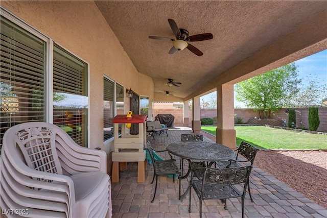 view of patio featuring outdoor dining area, a fenced backyard, and a ceiling fan