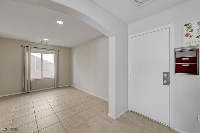 spare room featuring visible vents, baseboards, arched walkways, and light tile patterned flooring
