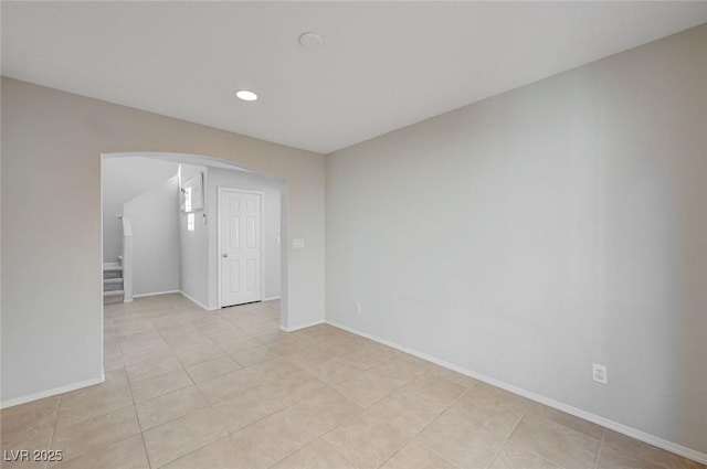unfurnished room featuring light tile patterned floors, baseboards, recessed lighting, and arched walkways