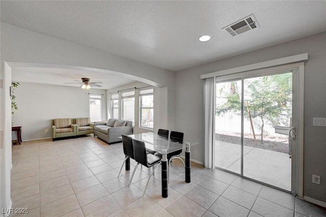 dining room featuring arched walkways, baseboards, a ceiling fan, and visible vents