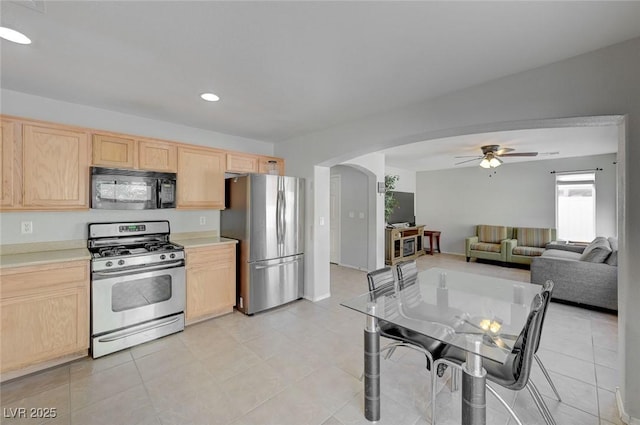 kitchen with ceiling fan, appliances with stainless steel finishes, arched walkways, and light brown cabinets
