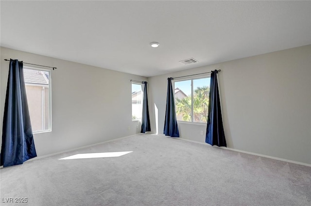 spare room featuring plenty of natural light, carpet flooring, visible vents, and baseboards