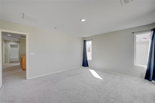 unfurnished room with visible vents, light colored carpet, baseboards, and a healthy amount of sunlight