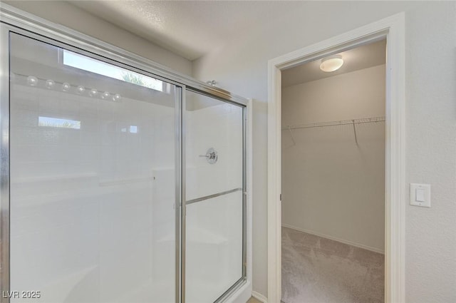 bathroom with a stall shower, baseboards, and a spacious closet