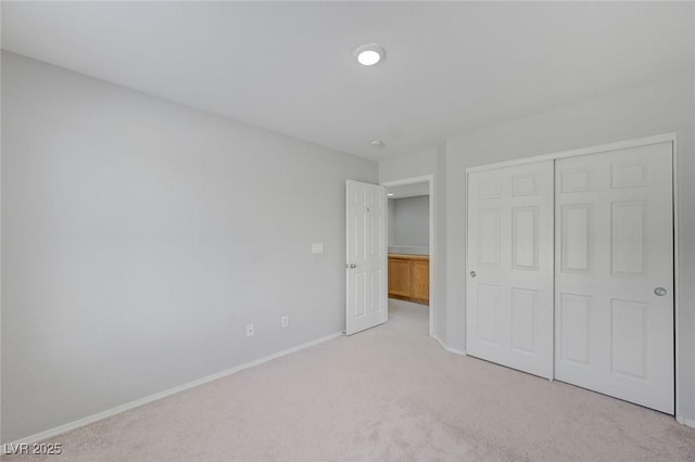 unfurnished bedroom with light carpet, a closet, and baseboards
